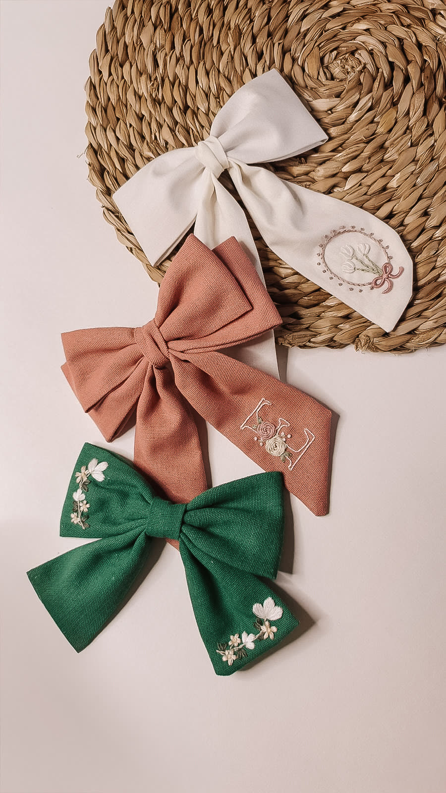 Três laços de linho bordados em creme, terracota e verde