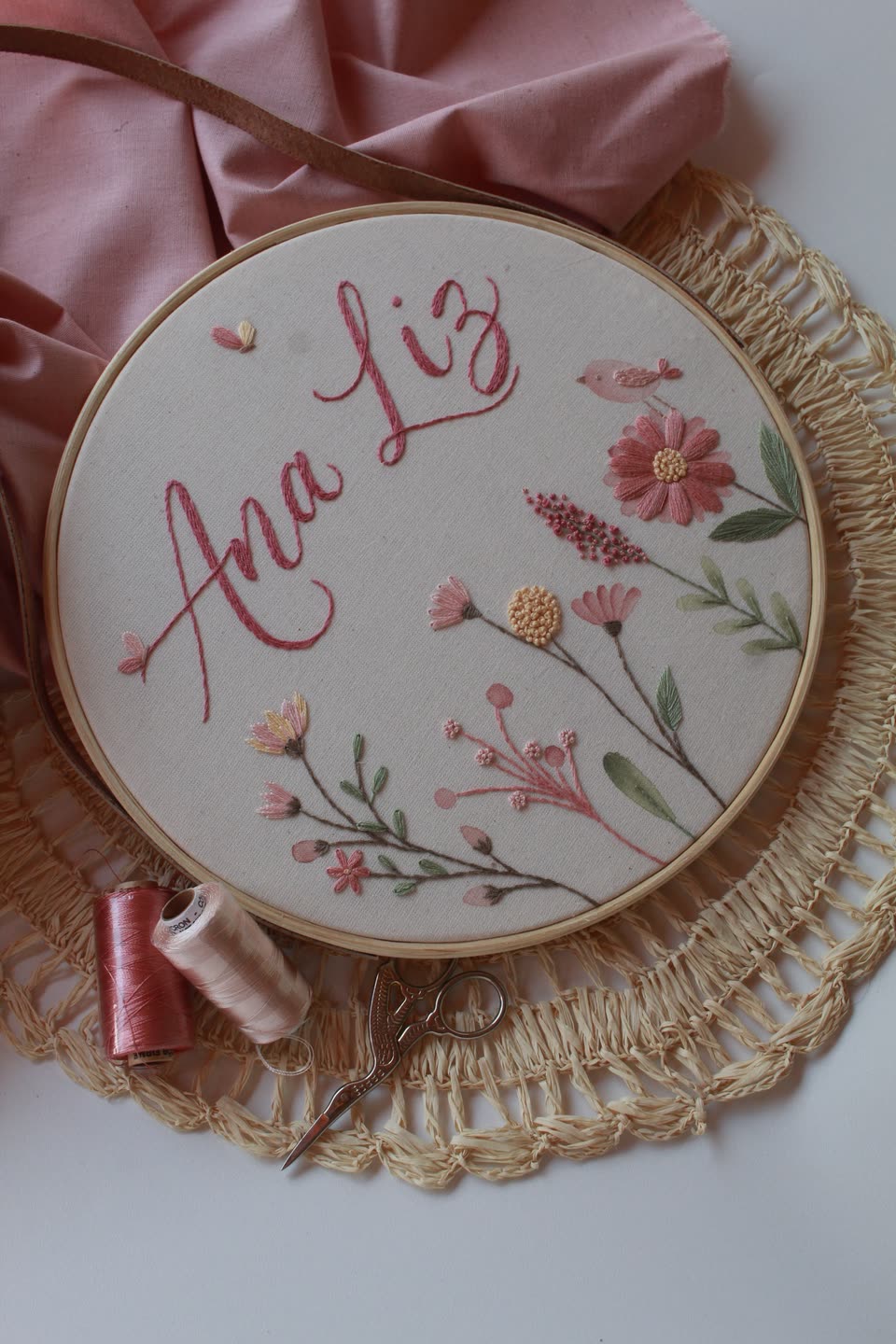 Porta-maternidade em bastidor com o nome Ana Liz e flores rosadas bordadas