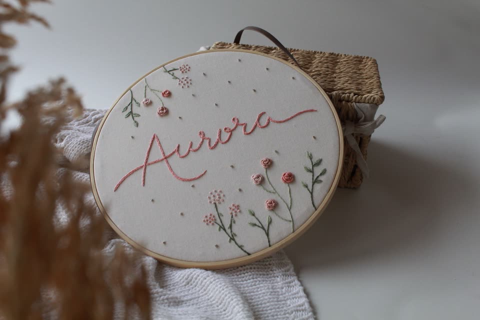 Porta-maternidade em bastidor com o nome Aurora e florzinhas bordadas