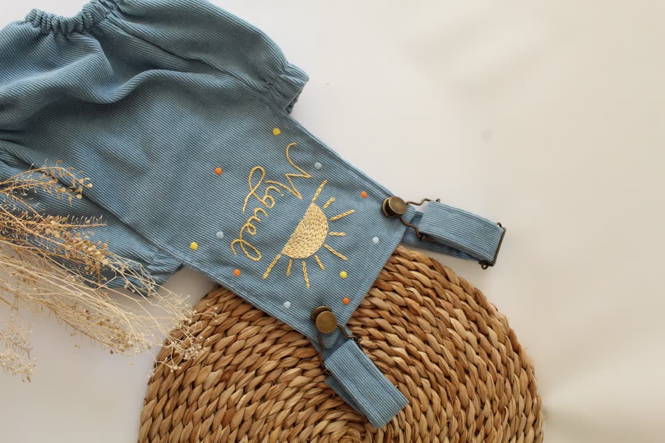 Jardineira azul com sol e o nome Miguel bordados